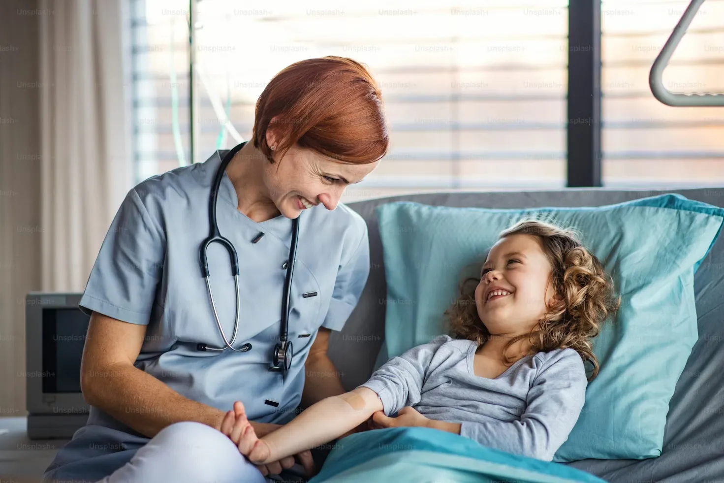 Medicinska sestra razgovara s nasmijanom djevojčicom